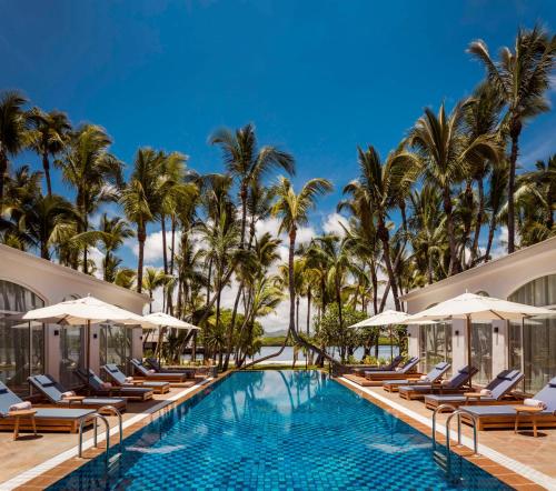 a pool at the resort with lounge chairs and palm trees at One&Only Le Saint Géran, Mauritius in Belle Mare