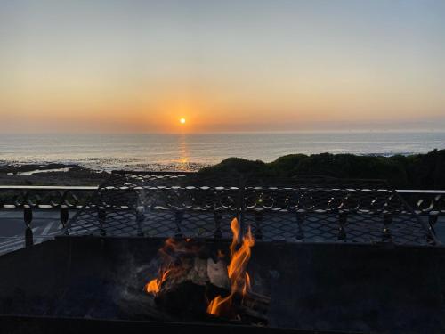 a fire pit on the beach with the sunset in the background at Casa Balena - Gansbaai seafront accommodation, back-up power in Gansbaai