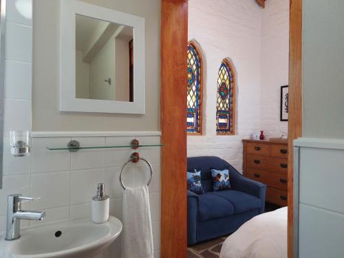 ein Badezimmer mit einem Waschbecken und einem blauen Stuhl in der Unterkunft Bethesda Tower Accommodation in Nieu-Bethesda