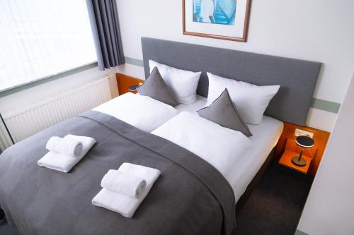 1 dormitorio con 1 cama grande y toallas blancas. en HOTEL BREMER TOR, Bestes Hotelfrühstück, Self-Check-In 24 h en Vechta