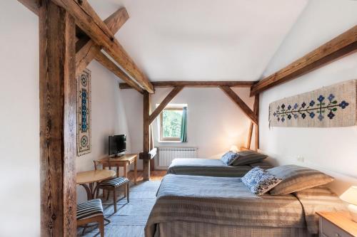 two beds in a room with wooden beams at Pałac Nieznanice Zabytek Gościnny ze SPA in Nieznanice