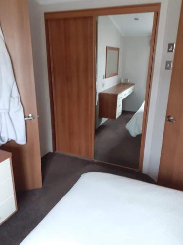 a bedroom with a mirror and a bathroom with a sink at 19 orchid Meadows in Newbiggin-by-the-Sea