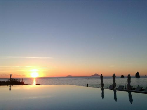 a infinity pool with the sunset in the background at Agriturismo Santa Margherita in Gioiosa Marea