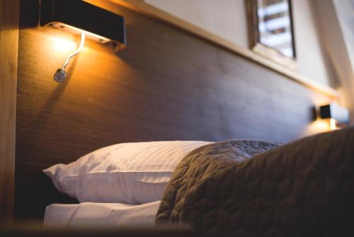 a bedroom with a bed with a wooden headboard and a light at Penzión ÁTRIUM in Prešov