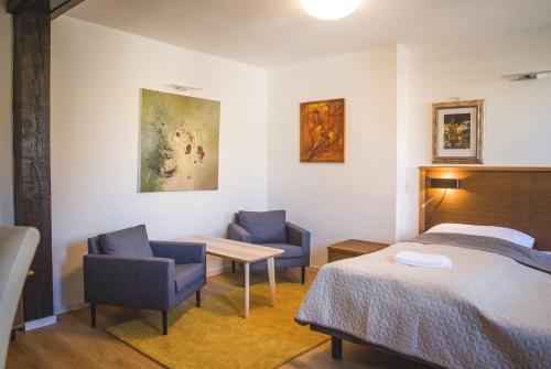 1 dormitorio con 1 cama, 2 sillas y mesa en Penzión ÁTRIUM en Prešov