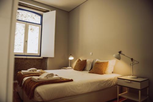 een slaapkamer met een bed met een lamp en een raam bij Estação Ferroviária de Codeçoso in Celorico de Basto
