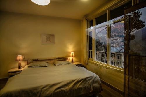 a bedroom with a bed and a large window at NomadGao Dharamkot - Work-Friendly Comfort Stay With a View in McLeod Ganj