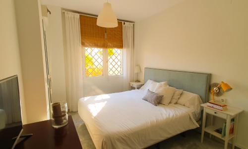 a bedroom with a white bed with a window at Vive la vida: Torremolinos (1ª línea) in Torremolinos