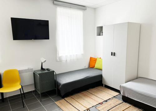 a room with a bed and a tv and a chair at Árkádia Vendégház in Lábatlan
