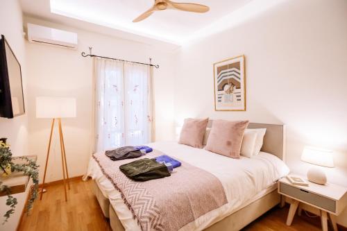 a white bedroom with a bed with a ceiling fan at Deviazi 4 in Zakynthos Town