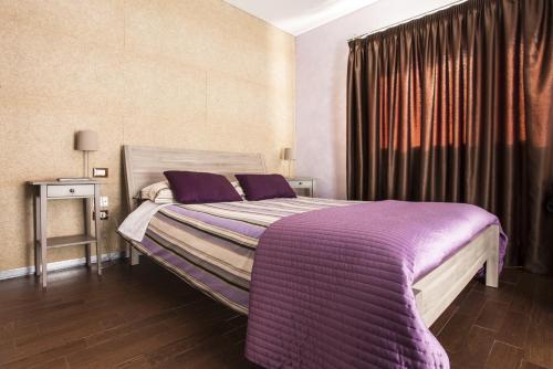 um quarto com uma cama com um cobertor roxo em Garden Holiday em Marina di Melilli