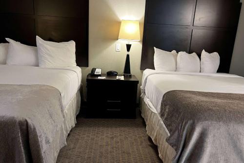 a hotel room with two beds and a table with a lamp at Baymont by Wyndham College Station in College Station