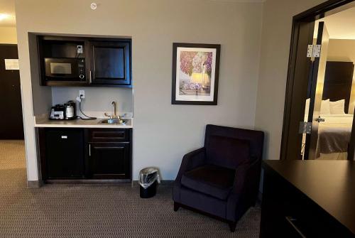a hotel room with a chair and a microwave at Baymont by Wyndham College Station in College Station