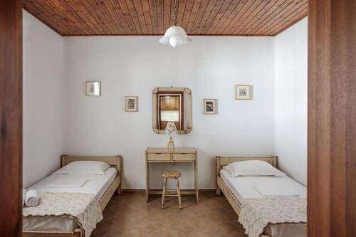 "Triacanthos" 3 bedroom house في Moutsoúna: سريرين في غرفة مع مرآة وطاولة