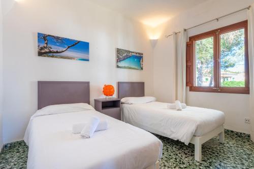 two beds in a room with white walls and a window at Casa Ca'n Munar in Portocolom