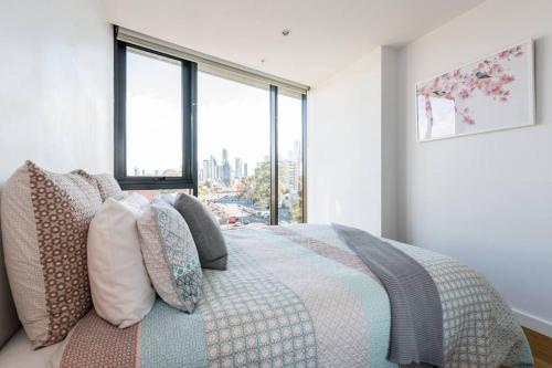 a bedroom with a bed with pillows and a window at South Melbourne Short Stay Luxury & Location 01728 in Melbourne