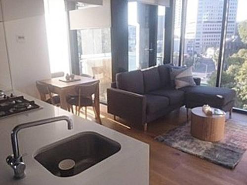 a kitchen and living room with a couch and a table at South Melbourne Short Stay Luxury & Location 01728 in Melbourne