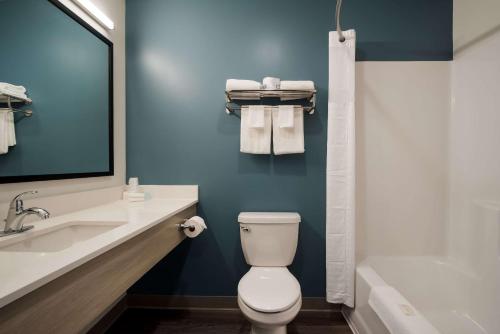 a bathroom with a toilet and a sink and a tub at WoodSpring Suites Grand Rapids Kentwood in Grand Rapids