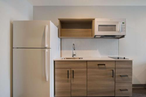 a kitchen with a white refrigerator and a microwave at WoodSpring Suites Grand Rapids Kentwood in Grand Rapids