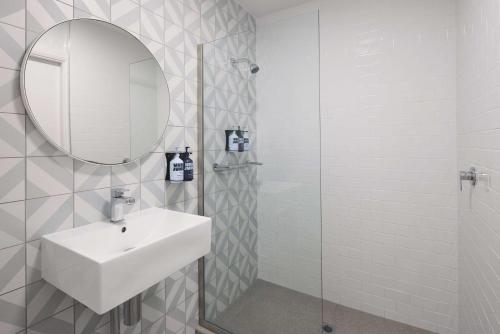 a white bathroom with a sink and a mirror at The Ultimo in Sydney