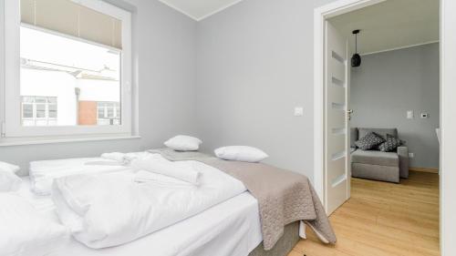 a white bedroom with a white bed and a window at Bursztynowe Osiedle Jantar, Sun & Snow in Jantar