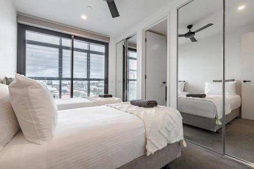 a bedroom with two beds and a large window at Lovely 2 bedroom apt with views to South Yarra - 03178 in Melbourne
