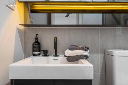 a bathroom sink with a bottle of wine and towels at Lovely 2 bedroom apt with views to South Yarra - 03178 in Melbourne