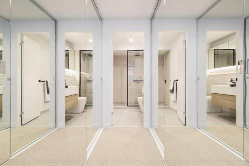 een badkamer met glazen deuren, wastafels en toiletten bij Nice 2-bed rental unit with free parking in Melbourne