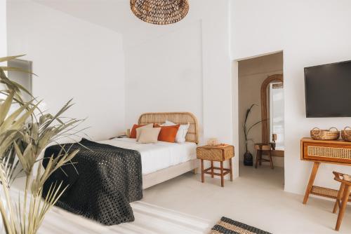a white bedroom with a bed and a tv at Divino Caldera in Akrotiri