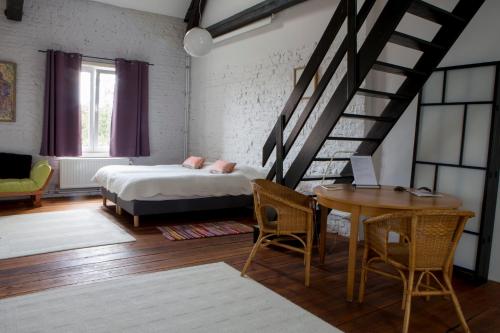 a bedroom with a bed and a table and a staircase at Les Greniers de Madelgaire in Soignies