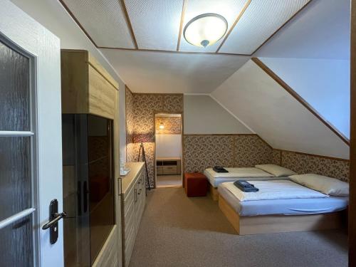 a bedroom with two beds and a bathroom with a ceiling at Hotel Veveří in Veverská Bítýška