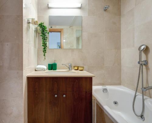 W łazience znajduje się umywalka, wanna i lustro. w obiekcie Dream Suite by the beach - Parking & Pool & Gym w mieście Herzliya