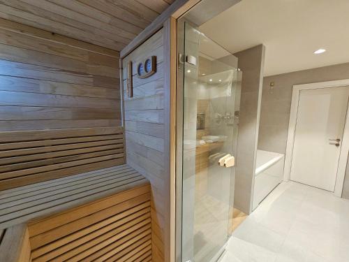 a walk in shower in a bathroom with wooden walls at Hotel ETNA in Gračanica