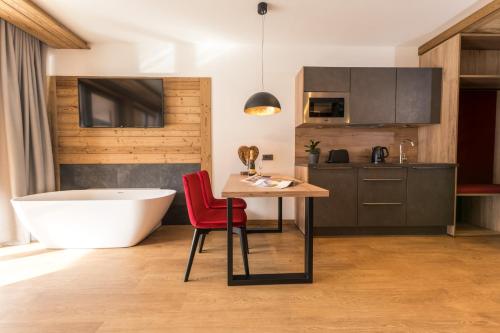 a bathroom with a tub and a table with a red chair at Alpin Peaks in Turracher Hohe