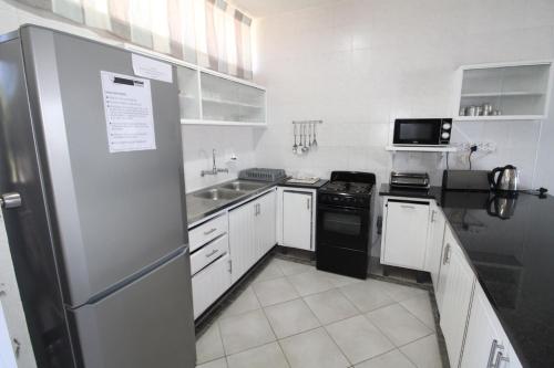 a kitchen with white cabinets and a black refrigerator at Seagull 507 in Margate