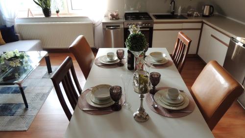 a dining room table with a white table cloth and chairs at Zielone Tarasy na Kaszubach in Sikorzyno