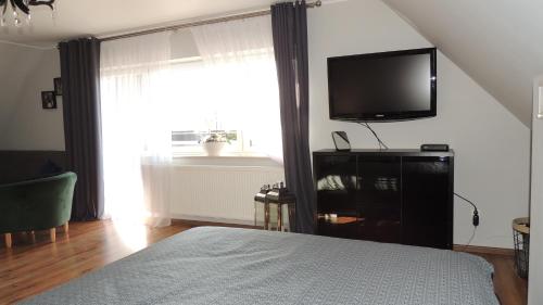 a bedroom with a bed and a flat screen tv at Zielone Tarasy na Kaszubach in Sikorzyno
