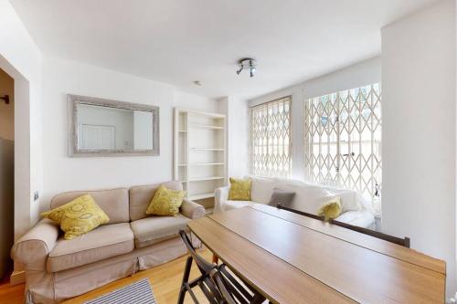uma sala de estar com um sofá e uma mesa em Cosy 2 bedroom Garden Flat in West Kensington em Londres
