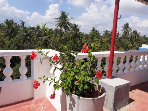 a white fence with red flowers on a balcony at Holi-Wood Guesthouse in Puducherry