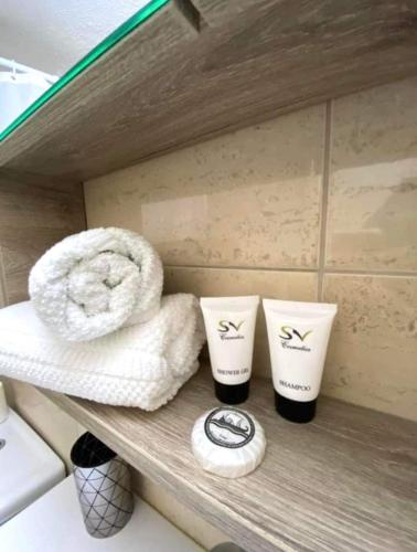 two towels and two cups on a shelf in a bathroom at Jasmin Apartments Brown in Hanioti