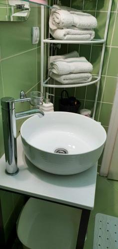 a bathroom with a sink and towels on a shelf at Apartman Studio DIAMOND in Subotica
