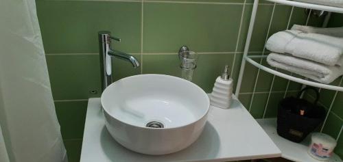 a white sink in a bathroom with green tiles at Apartman Studio DIAMOND in Subotica