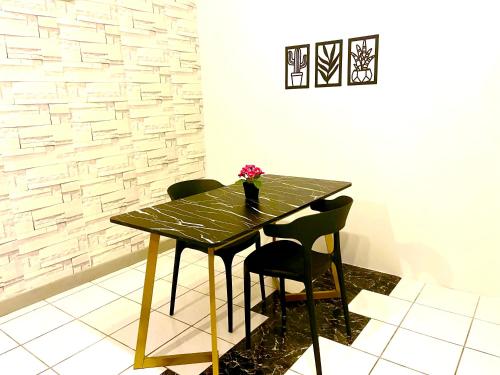 a wooden table with two chairs and a vase with flowers on it at Selesa hill homestay in Bentong