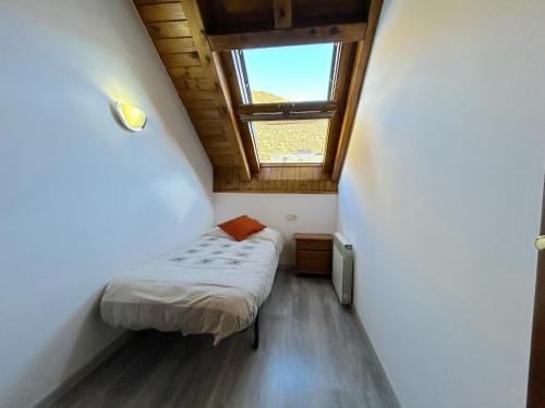 Habitación pequeña con cama y ventana en Dúplex lluminós a Esterri d'Àneu by RURAL D'ÀNEU, en Esterri d'Àneu