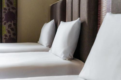 two beds with white pillows in a hotel room at Esplanade Hotel Llandudno in Llandudno