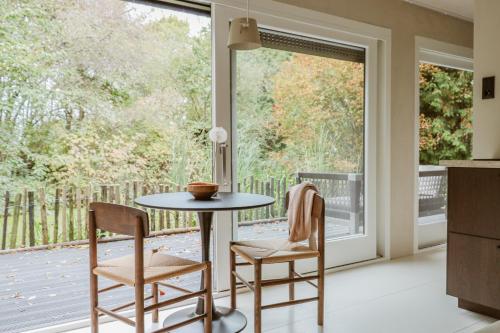 a kitchen with a table and chairs in front of a window at Cabin Water Zuidermeer in Zuidermeer