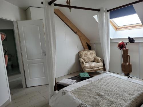 een slaapkamer met een bed, een stoel en een raam bij laurilia in Saint-Romain-sur-Cher
