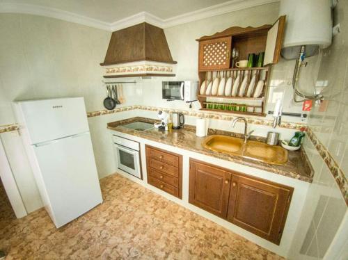 a kitchen with a sink and a white refrigerator at La Tienda de Miguel in El Chorro