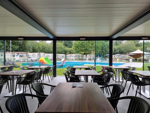 een cafetaria met tafels en stoelen en een zwembad bij Vakantiepark Breebos in Rijkevorsel