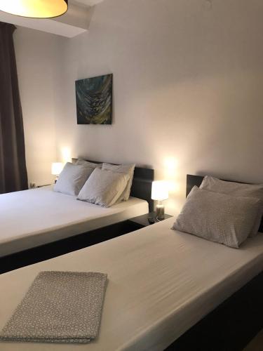 two beds in a small room with two lamps at Apartments IVI Gevgelija in Gevgelija